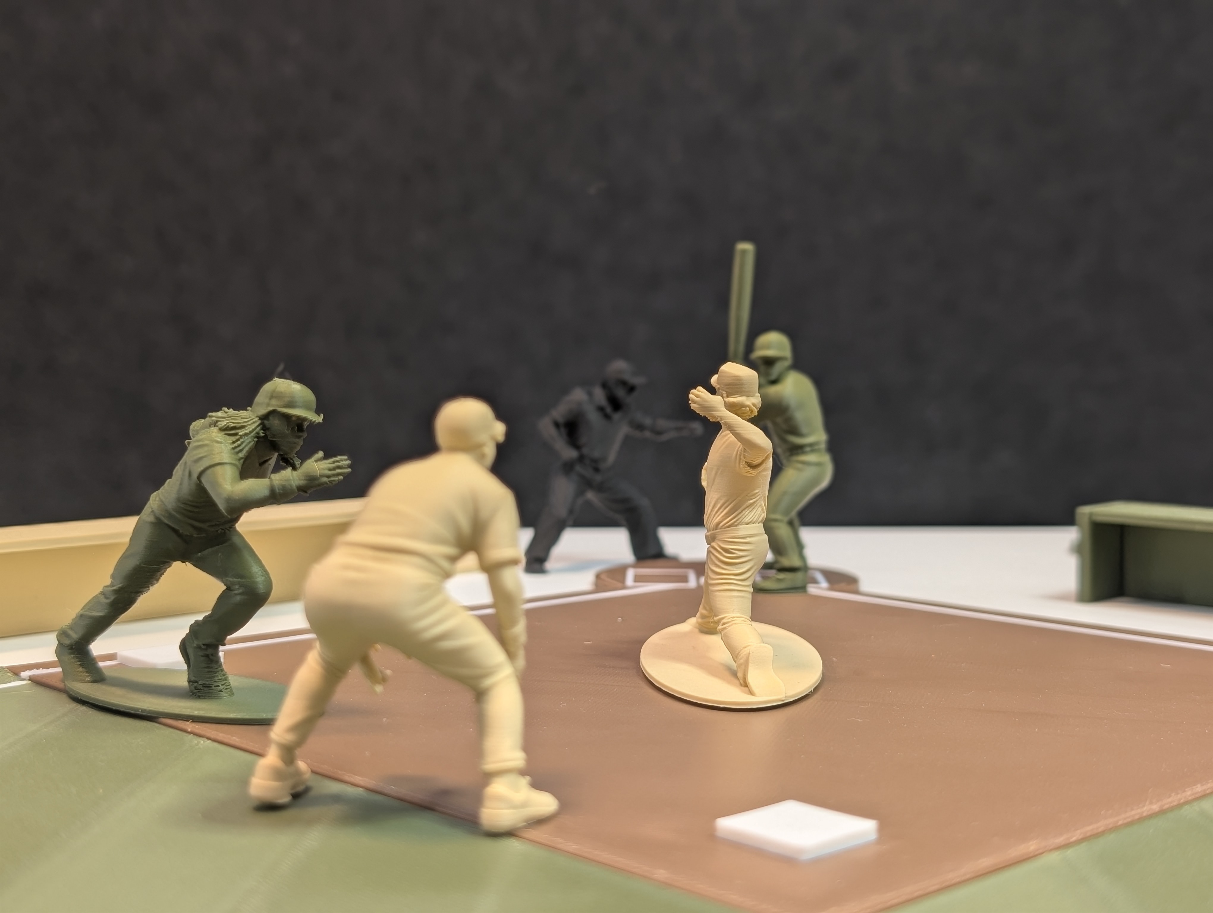 Multiple Baseball Army Men figurines positioned on the velvet field mid-play — green and tan teams facing off