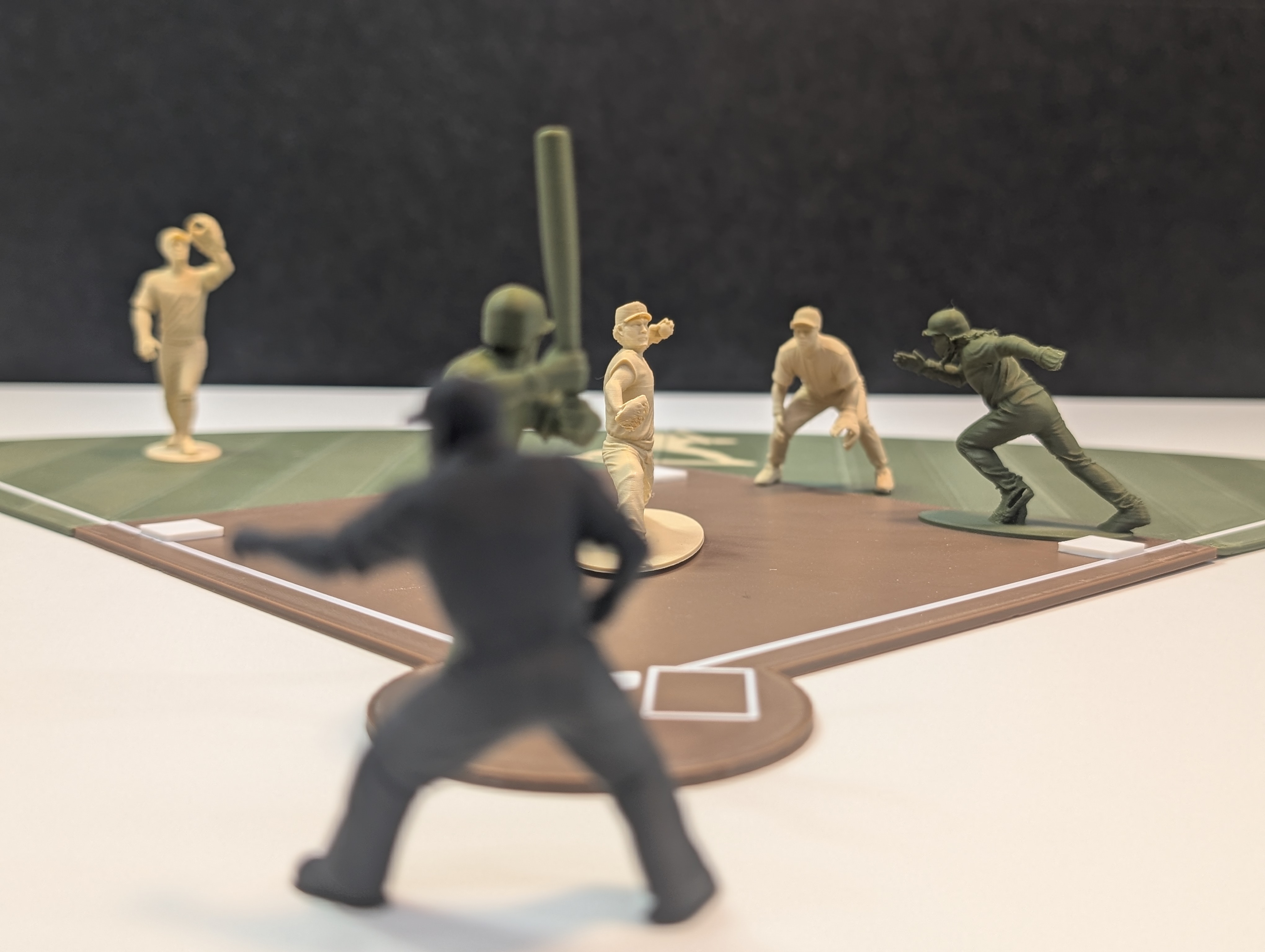 Baseball Army Men figurines in live play — cinematic low-angle shot showing multiple positions on the velvet field